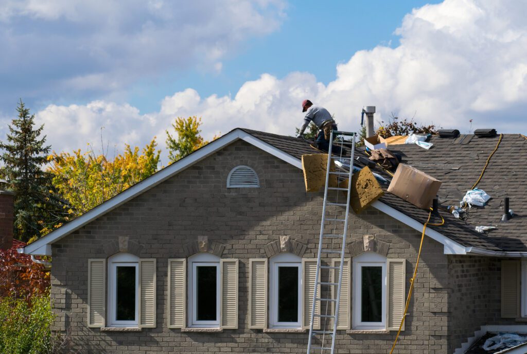 Roofing worker on the roof of a 2-story family house