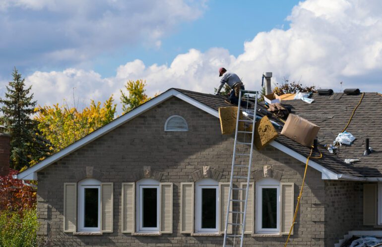 Roofing worker on the roof of a 2-story family house